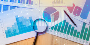 Magnifying glass and documents with analytics data lying on table,selective focus